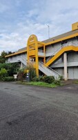 Um edifício com entrada amarela e escadaria que leva a um segundo andar.