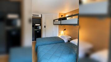 Un dormitorio con literas, un armario y un microondas.