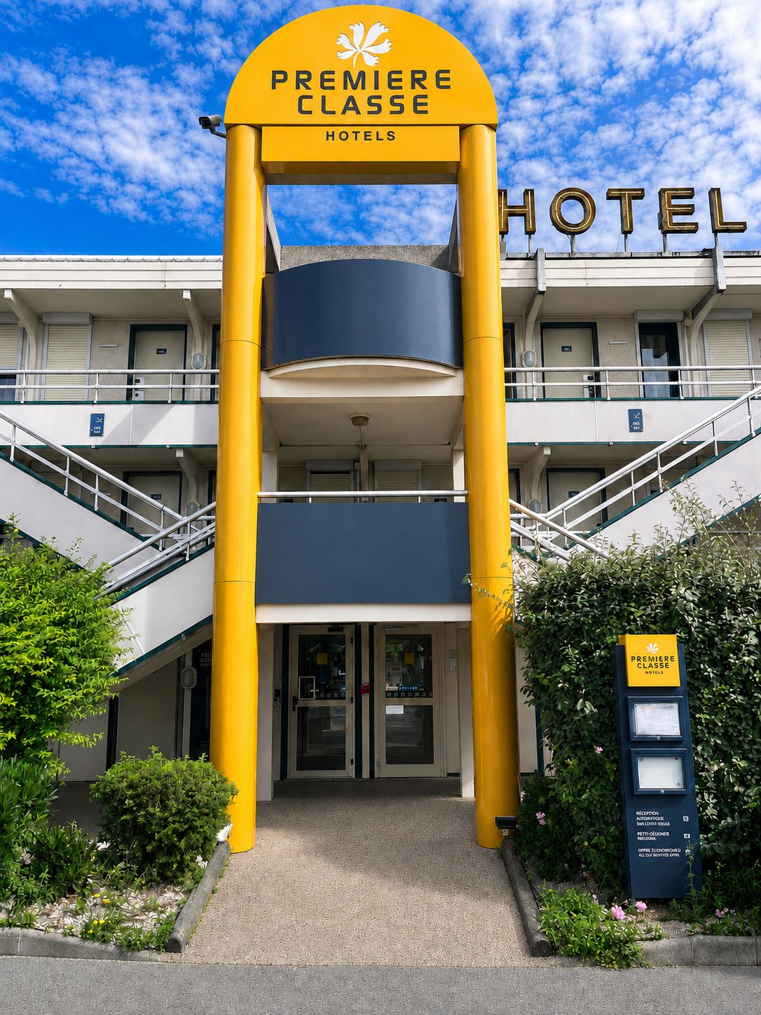 Entrada de un hotel con un arco prominente con la leyenda 'Premiere Classe Hotels' y un letrero que indica recepción automática.