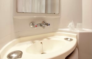 A bathroom with a white sink, a mirror, and two ice cubes on the edge. - Premiere Classe Compiègne - Jaux (Jaux)
