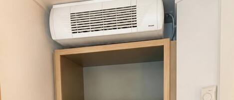 Una kitchenette compacta con aire acondicionado integrado, microondas y refrigerador.
