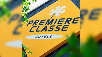 Un letrero con el texto 'PREMIERE CLASSE HOTELS' y un logotipo con un diseño floral estilizado.