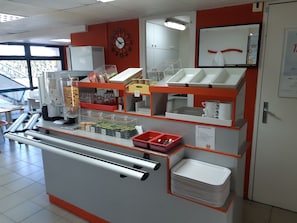 A self-service beverage station with dispensers, condiment containers, and a clock on the wall. - Premiere Classe Compiègne - Jaux (Jaux)