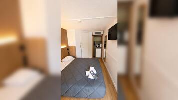 Ein kleines Hotelzimmer mit Bett, einer Küchenzeile und einem Kleiderschrank.