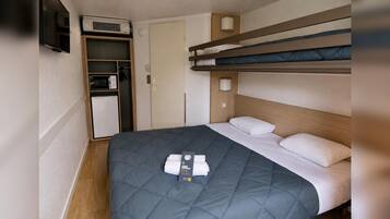 Una camera d'albergo compatta con letti a castello, angolo cottura e TV a schermo piatto.