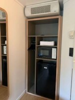 Uma cozinha compacta equipada com micro-ondas, frigorífico e forno embutido.