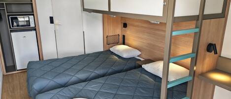Una cama litera con una cama inferior y una superior, ambas con ropa de cama azul. Hay una toalla blanca sobre la cama inferior.