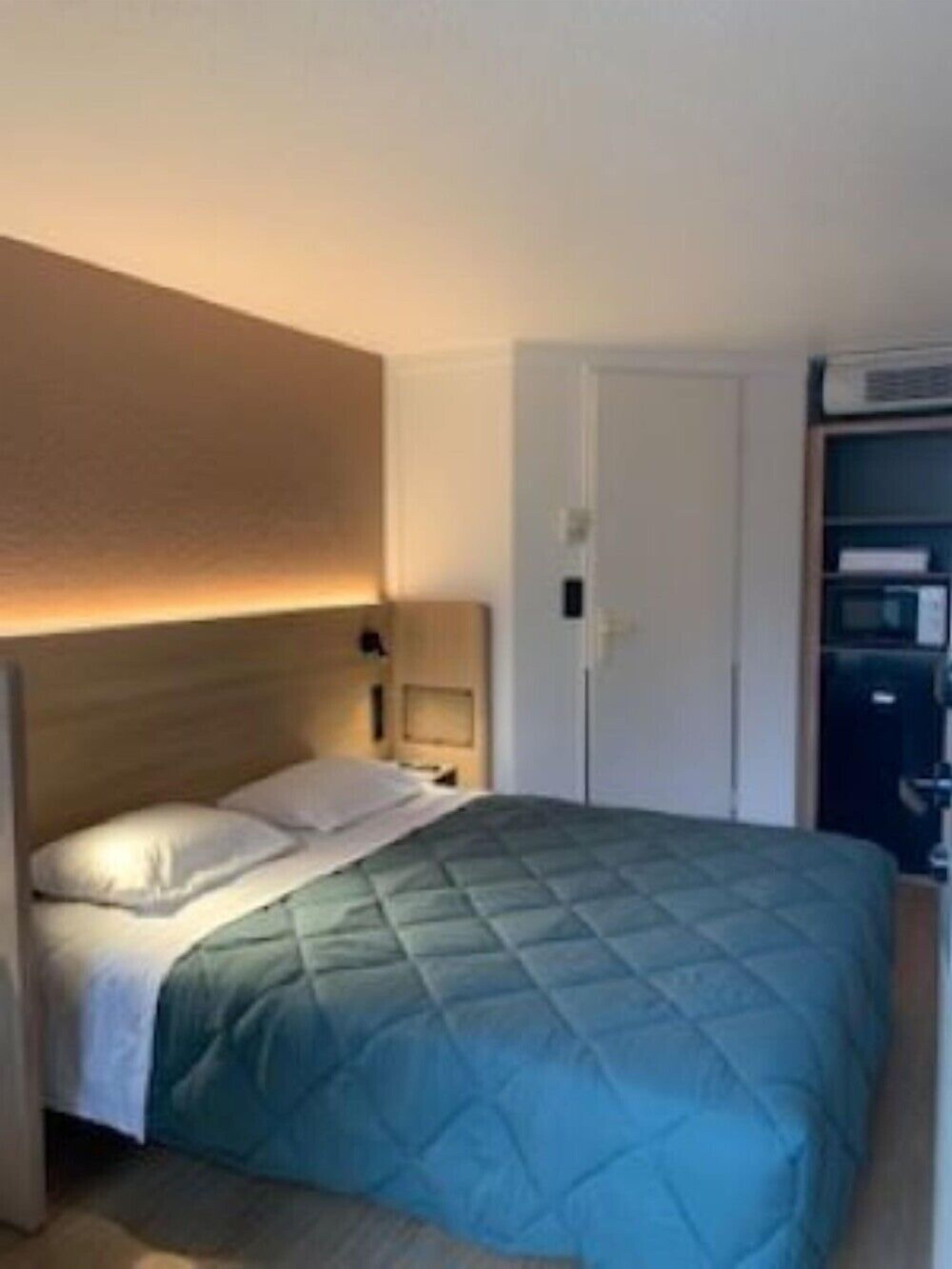 Une chambre à coucher comprenant un lit, des tables de chevet, une armoire et un radiateur encastré.