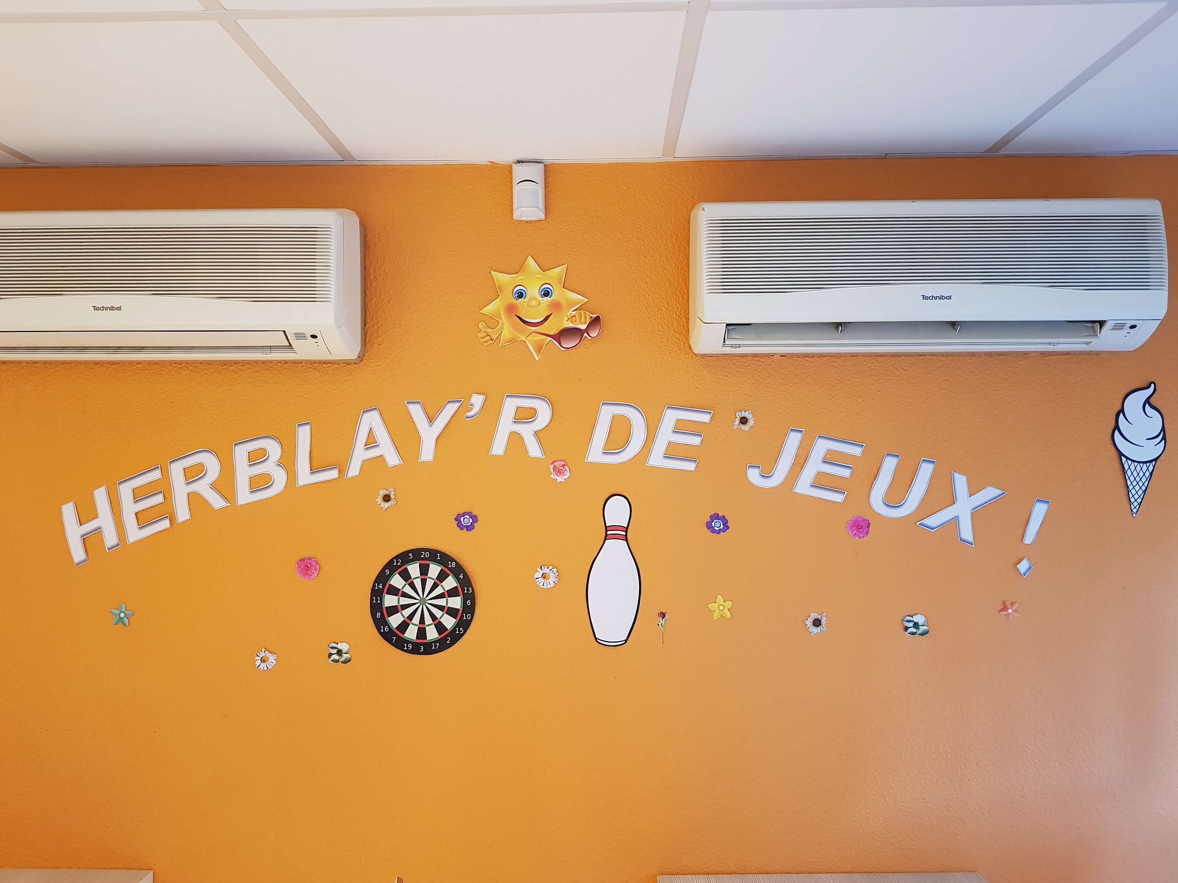 A wall with the text "HERBLAYR DE JEUX!" and two air conditioning units.