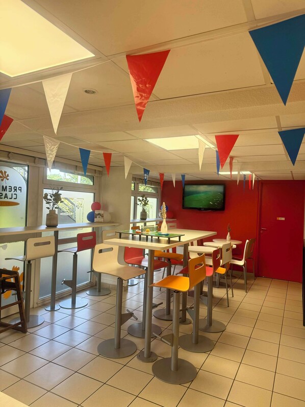 A restaurant with a red door, white and red triangular flags, and a TV on the wall. - Premiere Classe Herblay (Herblay)