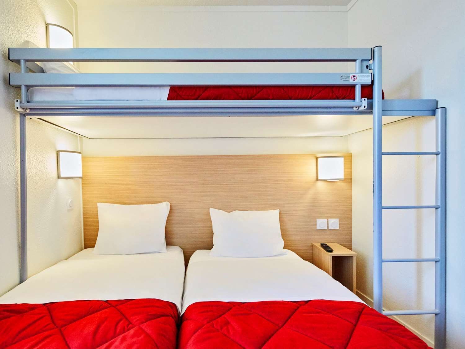 A bunk bed room with a wooden headboard, two bedside tables, and a red blanket.