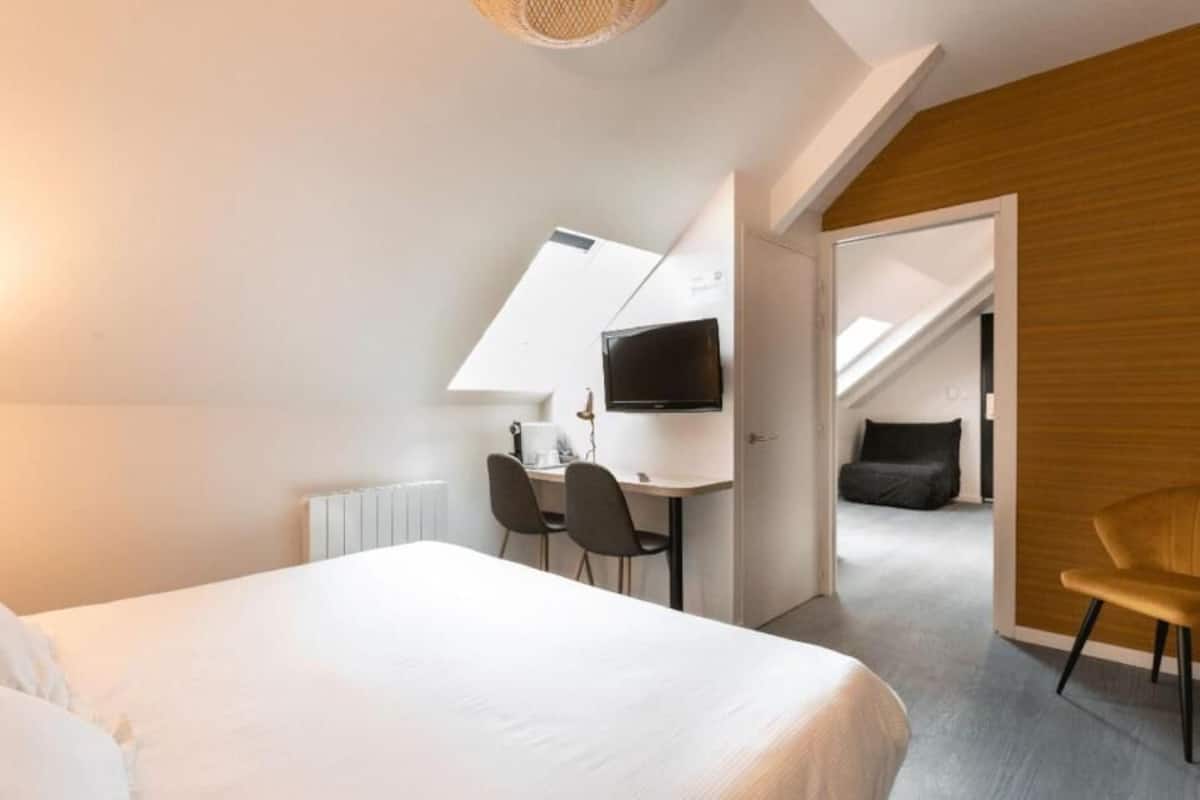 Een moderne hotelkamer met een bed, een bureau met stoel, een televisie en uitzicht op buiten.