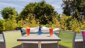 Mesa junto a la piscina con dos sillas, dos bebidas y una botella.