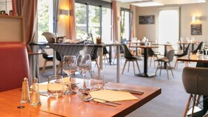 Un restaurante con mesas dispuestas para comer, amplias ventanas y una decoración de diseño moderno.