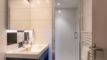Een moderne badkamer met een grote spiegel, een wastafel en een douchecabine met glazen wanden.