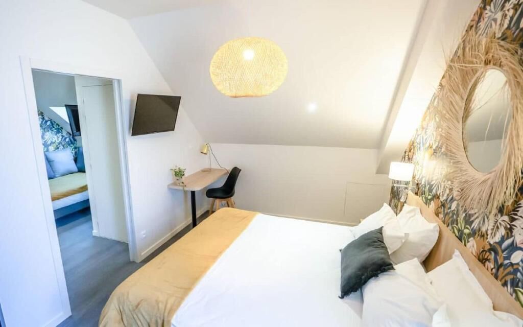 A bedroom with a bed, a desk, a chair, a television, and a decorative mirror.