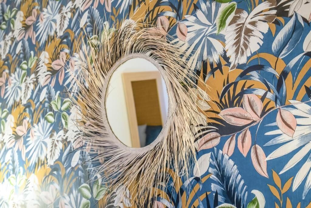A room with a mirror surrounded by a decorative wall with a tropical leaf pattern.
