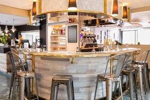 A bar area with a curved counter, stools, and a variety of bottles and glasses.