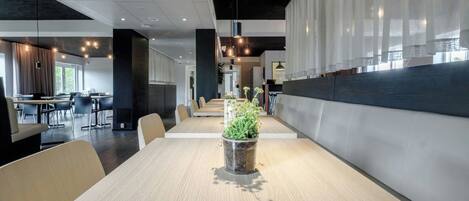 Una sala de conferencias moderna con una mesa larga, sillas y una planta en maceta.