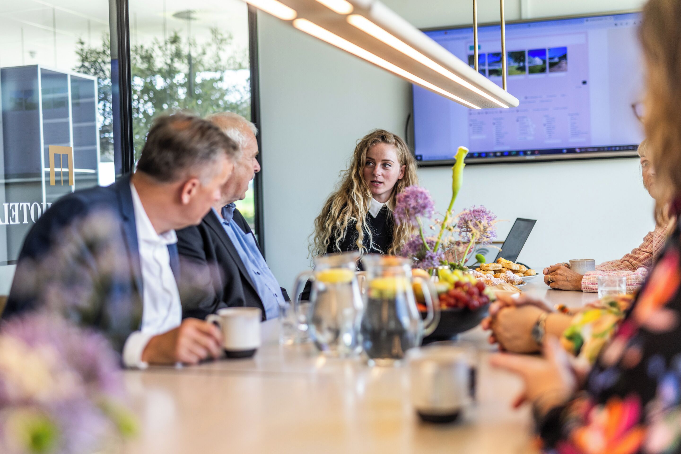 A meeting room with a table set for a group discussion, featuring a laptop, documents, and refreshments.