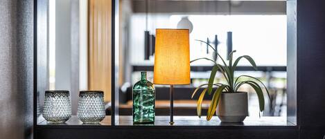 Una estantería con objetos decorativos, incluyendo una lámpara, una planta en maceta y cristalería.