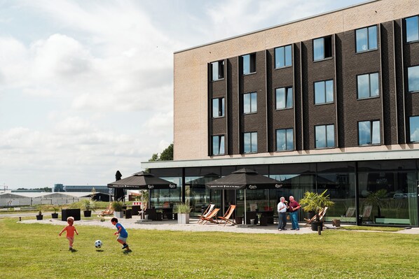 Un edificio moderno con techo plano, ventanas amplias y zonas de estar al aire libre.