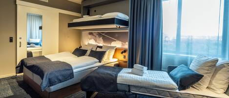 Habitación de hotel con literas, escritorio y vista a la ciudad.