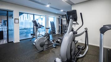 A gym with cardio machines, weight equipment, and a view of a snowy landscape through large windows.