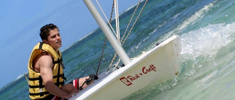 Una persona en un velero con el nombre "Rei + Cratt" en el costado.