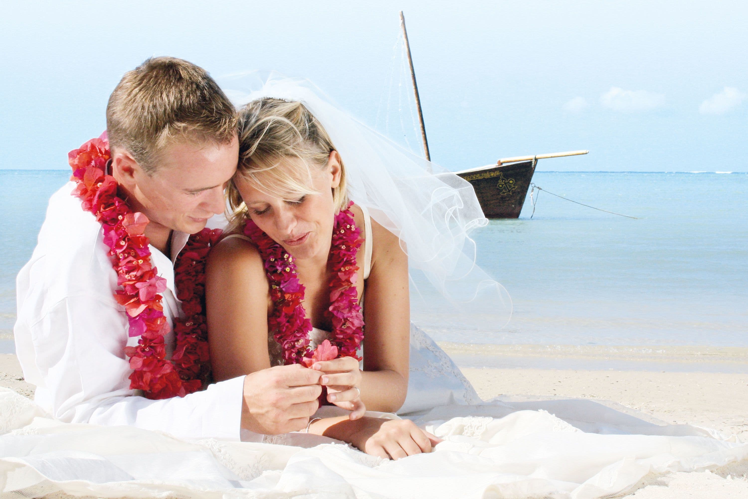 Un couple sur une plage, avec un bateau en arrière-plan.