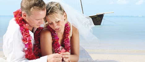 Una pareja en la playa, con un barco al fondo.