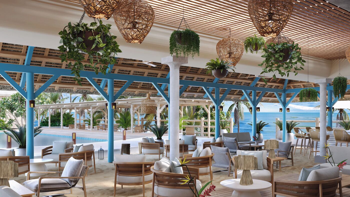 A covered outdoor seating area with wicker furniture, hanging plants, and a view of the ocean.