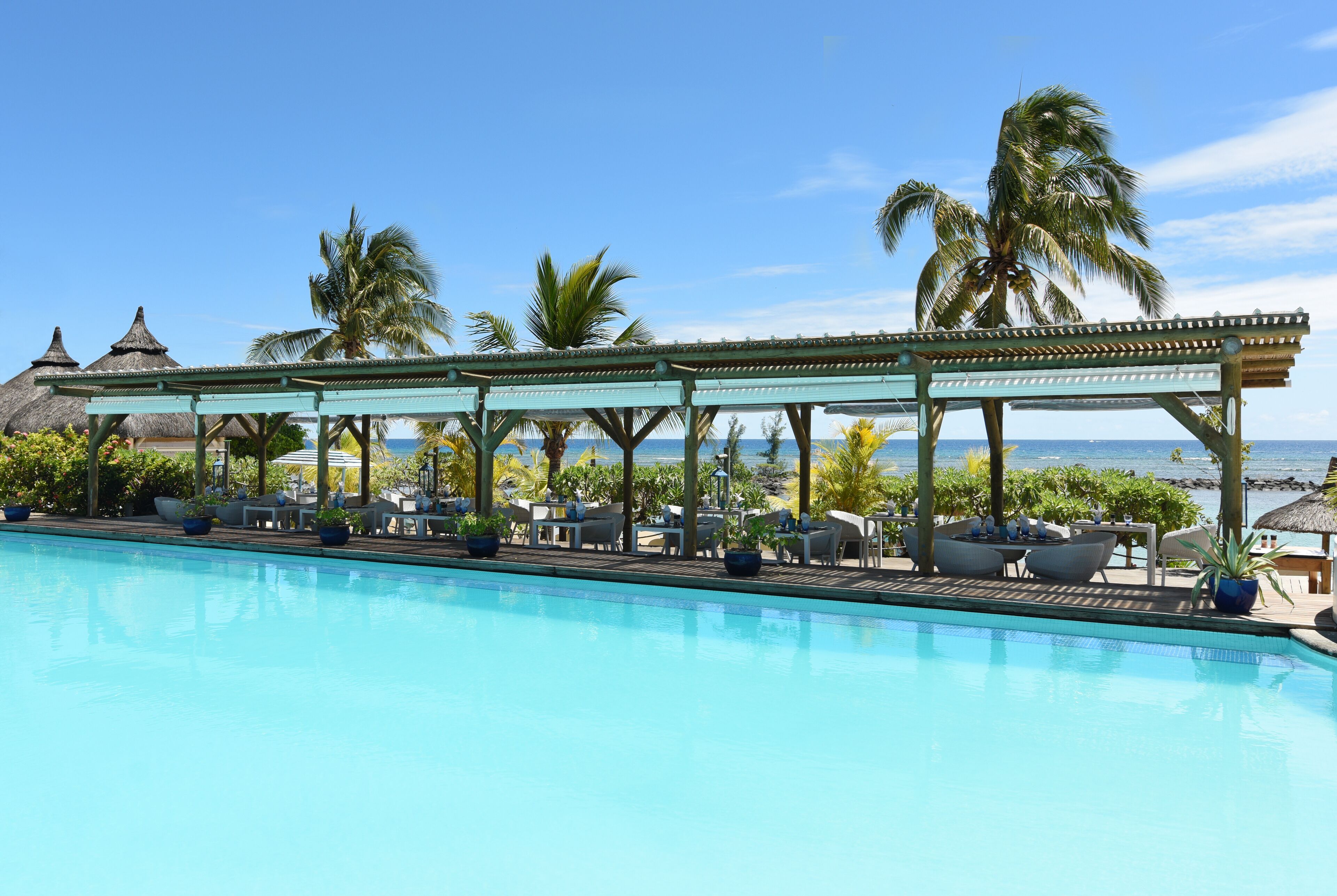 A poolside area with lounge chairs and a covered seating area overlooking the ocean.