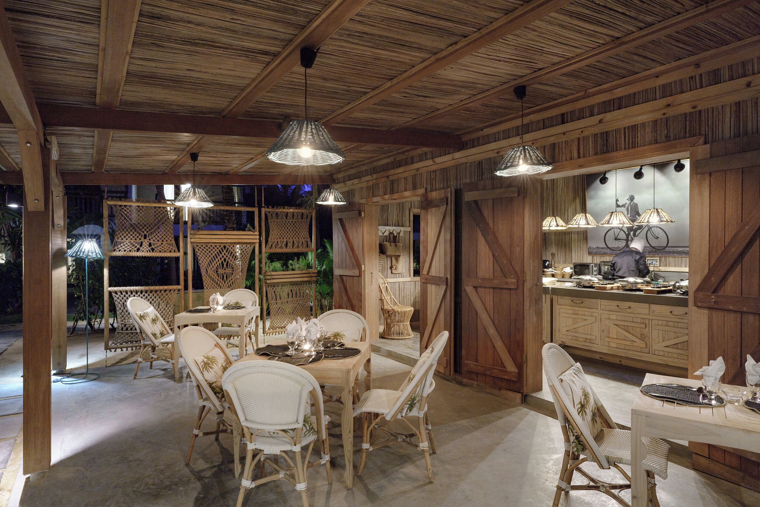 Un área de comedor al aire libre con mobiliario de mimbre e iluminación colgante.