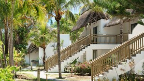Un resort con un edificio de techo de paja, una escalera de madera y exuberante vegetación tropical.