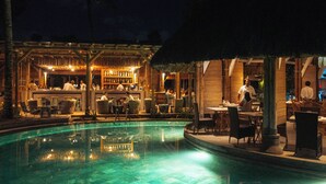 Zona de piscina exterior con bar y asientos.