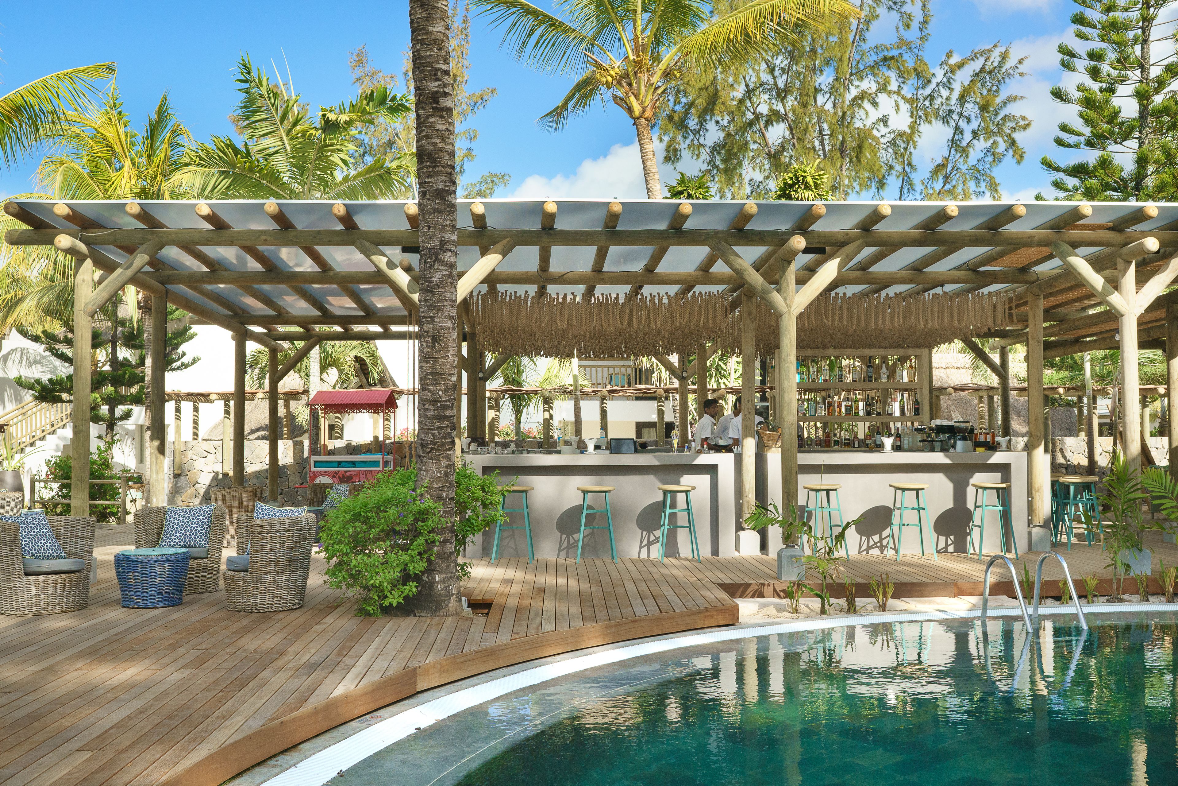 Ein Poolbereich mit Korbmöbeln, einer Bar und einer überdachten Lounge-Ecke.