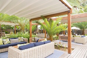 A covered outdoor seating area with wicker furniture and a wooden pergola. - Coin de Mire Attitude (Cap Malheureux)