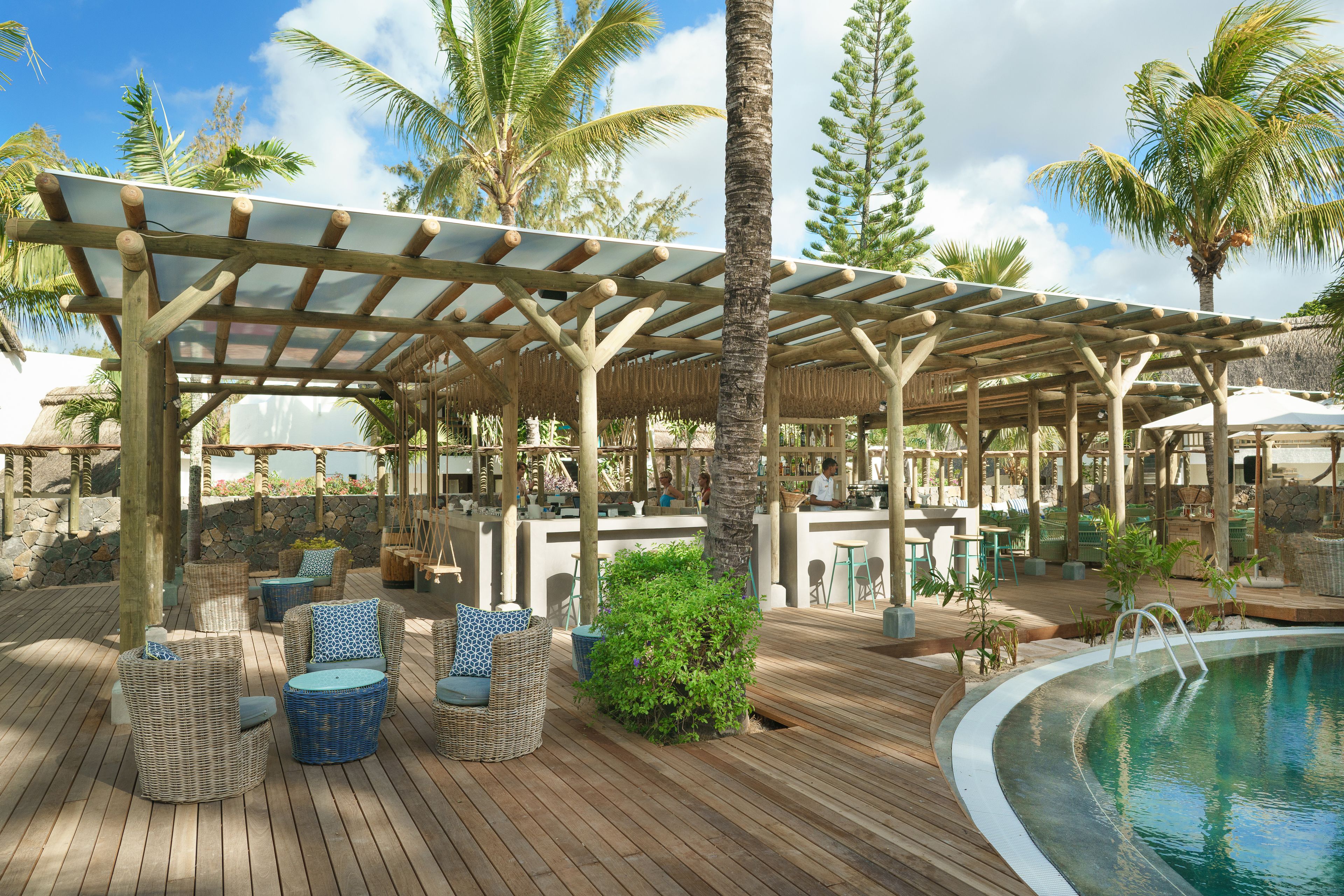 Un espace extérieur abrité, aménagé avec des meubles en osier et doté d’une piscine.