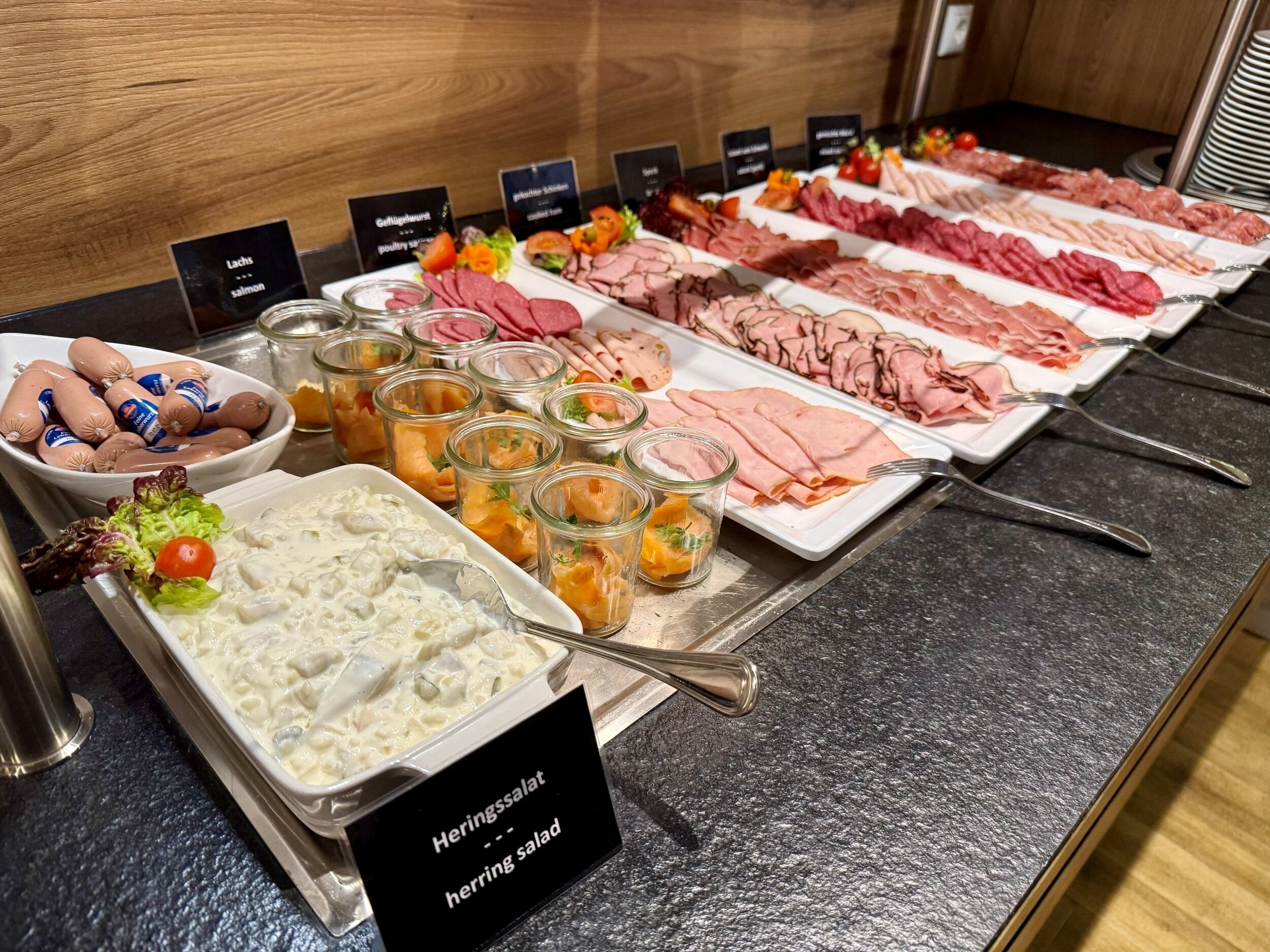 Ein Buffet mit verschiedenen Fleischsorten, Salaten und einem Heringssalat.