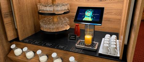 A self-service beverage station with multiple drink dispensers, a digital menu screen, and a glass carafe.