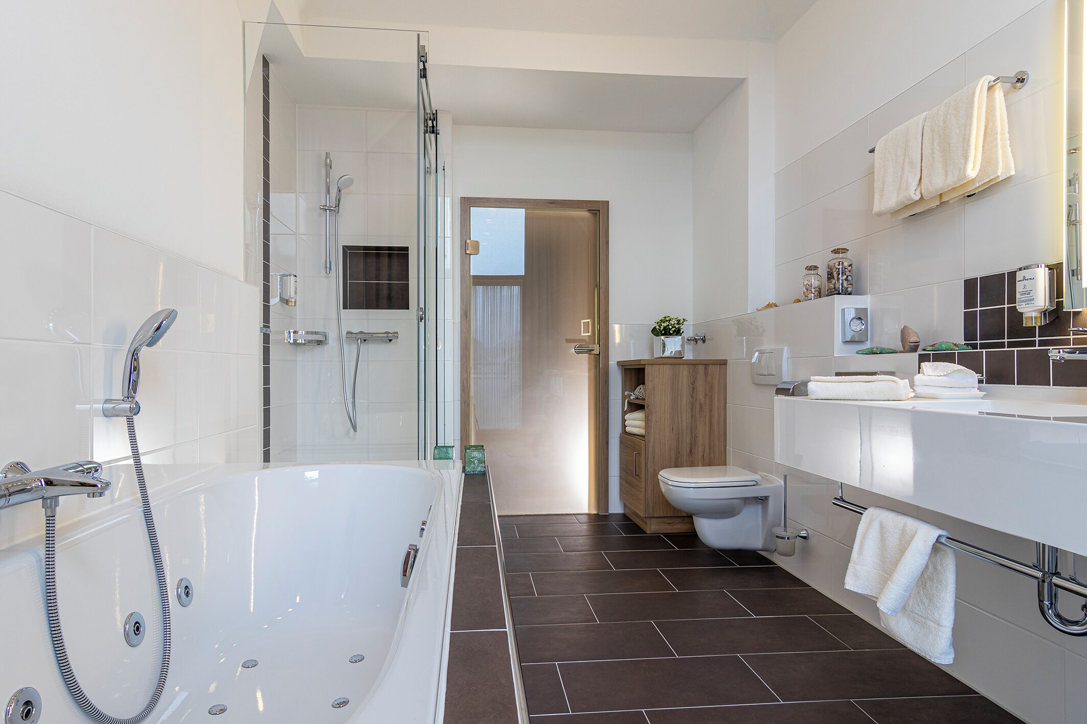 Une salle de bain moderne équipée d’une baignoire, d’une douche, de toilettes et d’un meuble-lavabo.