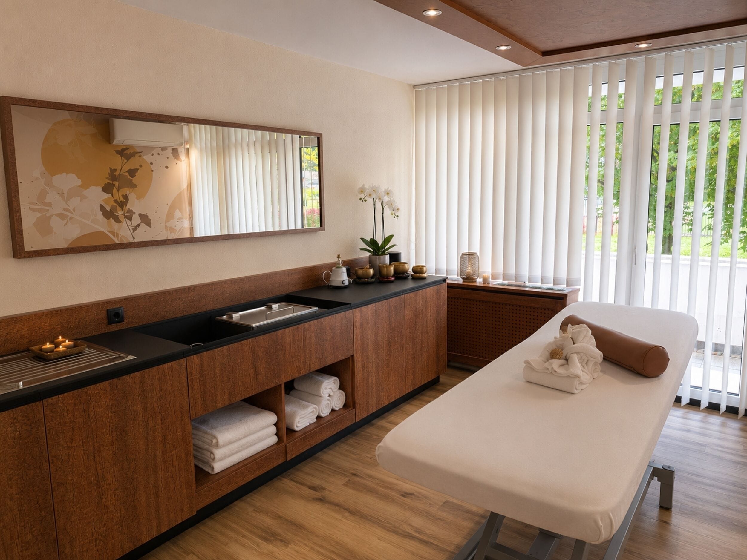 A modern bathroom with a wooden vanity, a large mirror, a sink, and a massage table.