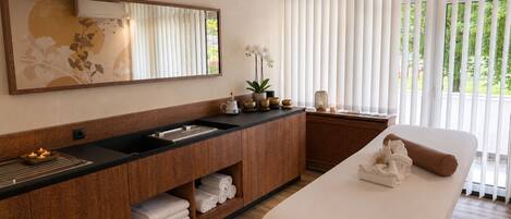 Un baño moderno con un tocador de madera, un espejo grande, un lavabo y una mesa de masaje.