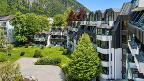 Un hotel moderno con numerosi balconi, un cortile interno e un panorama montuoso.