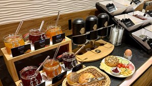 Un buffet della colazione con diverse marmellate, miele e pane.
