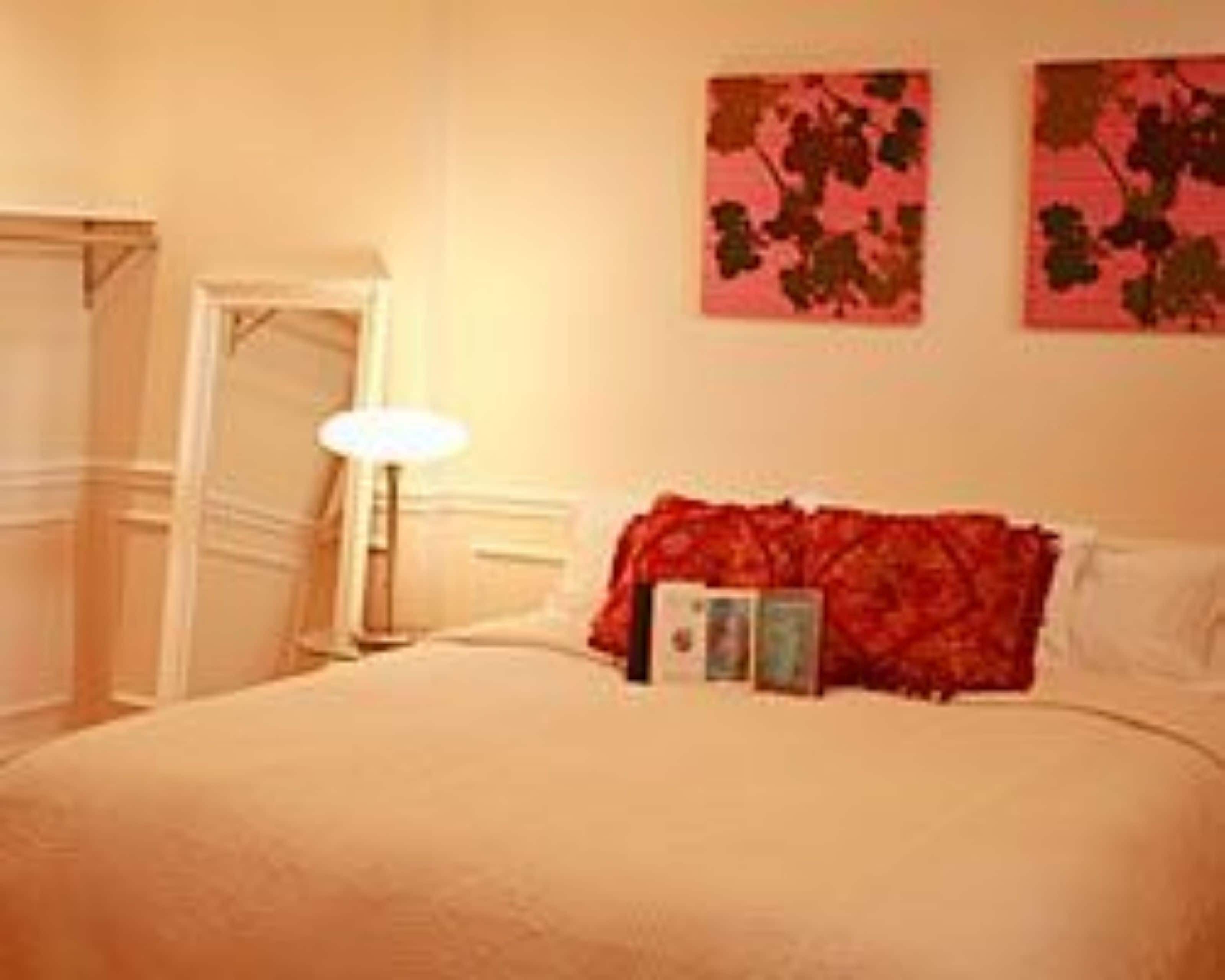 Een slaapkamer met een bed, nachtkastje, lamp en twee decoratieve wandpanelen.