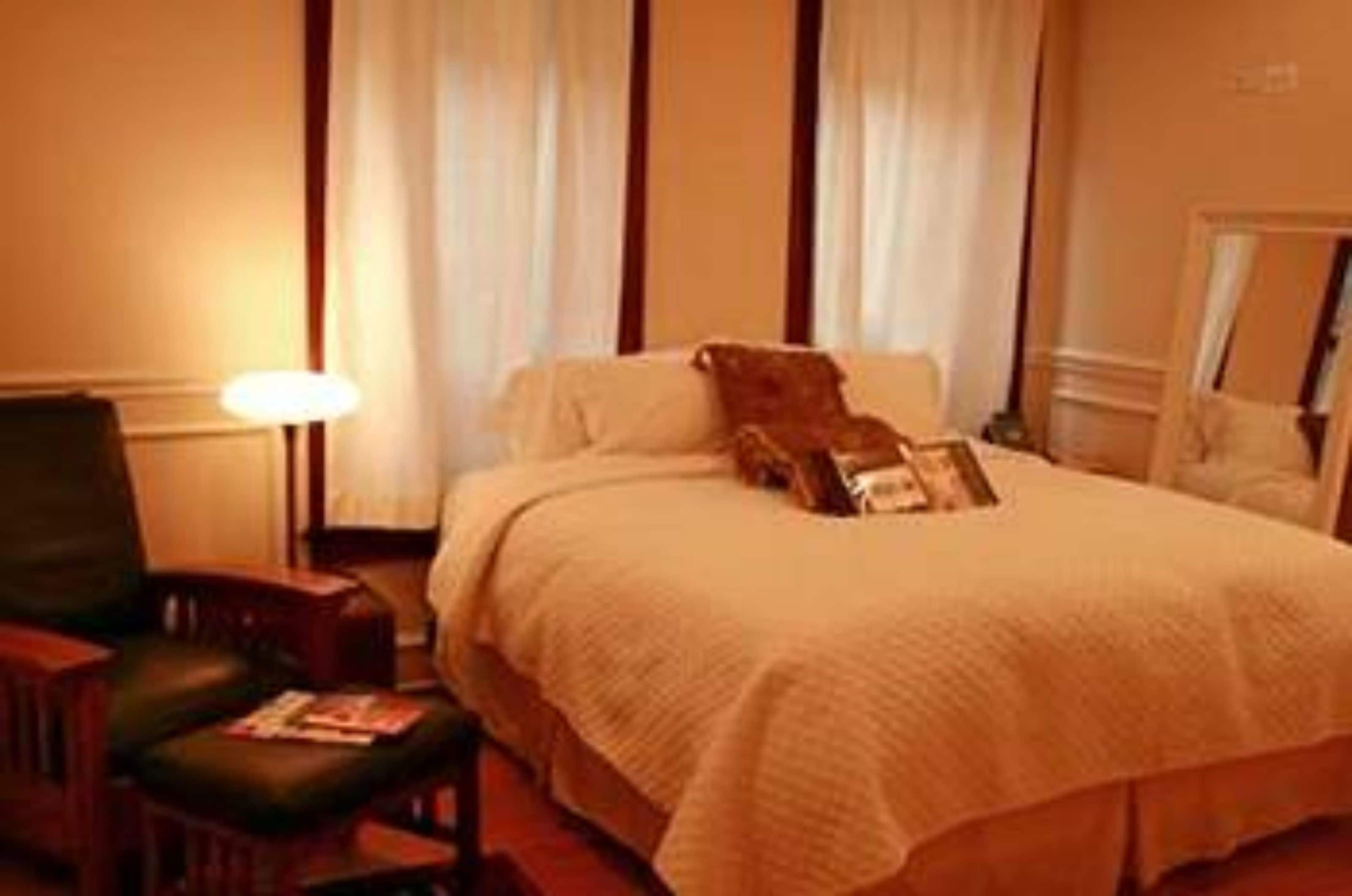 Une chambre d’hôtel avec un lit, une chaise, une lampe et un miroir.