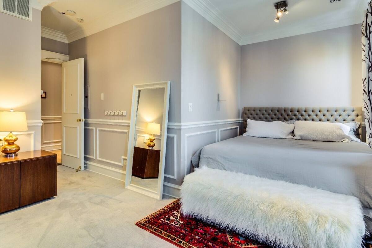 A bedroom with a large bed, a mirror, a dresser, and a nightstand.