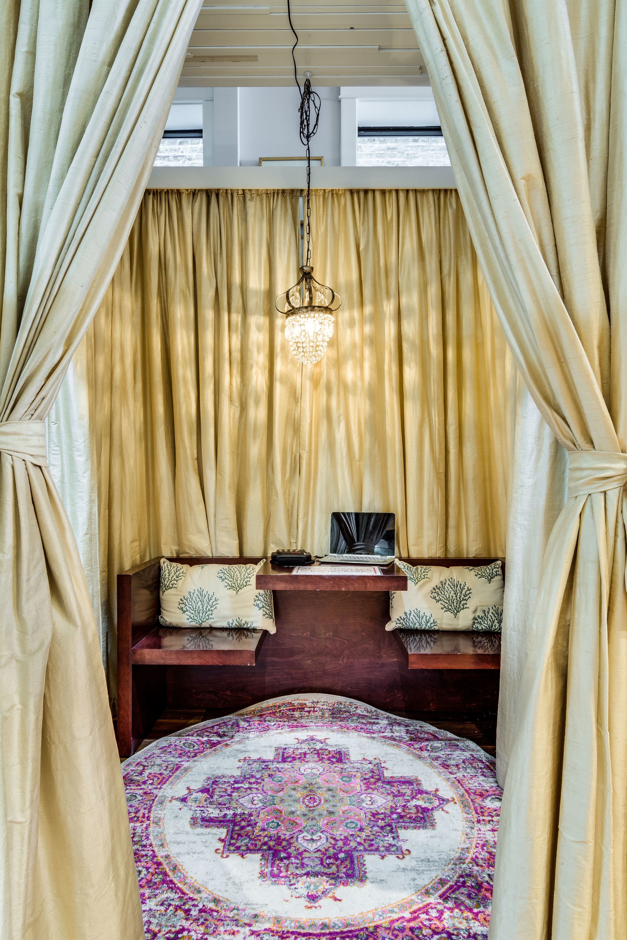A room with a bed, a desk, and a hanging light fixture.